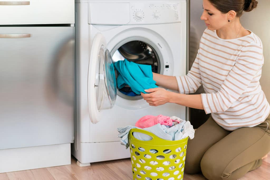 Woman loading laundry into a washing machine symbolizing customer experience, proactive monitoring, and managing negative reviews for a home appliance company focused on brand reputation, retailer partnerships, restoring confidence, and turning frustrated customers into loyal advocates