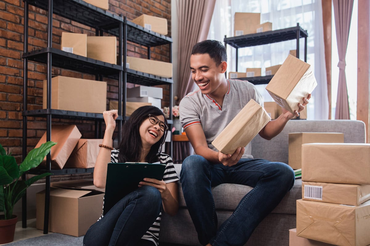 Two smiling while friends holding shipping packages