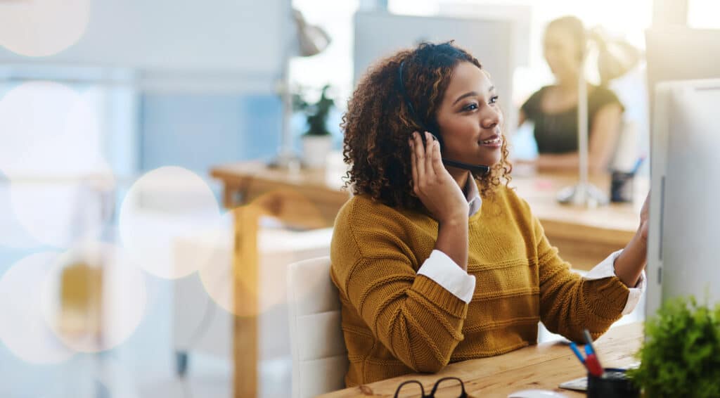 Inside sales representative on a call in a modern office environment, embodying traits for inside sales success. This image represents insights on how to be a successful inside sales rep and offers a glimpse into the day-to-day activities of a good inside sales rep.
