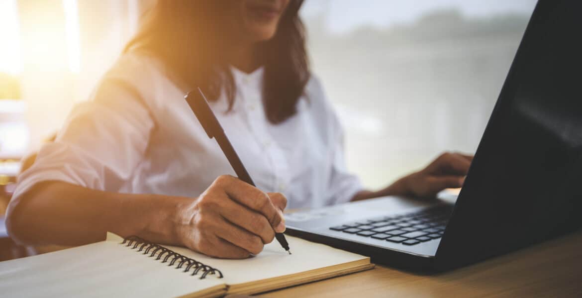 Inside sales representative taking notes during a client call, demonstrating the importance of industry immersion and personalized customer engagement in the sales process. This visual reflects the role of understanding industry trends and client-specific needs to achieve inside sales success.