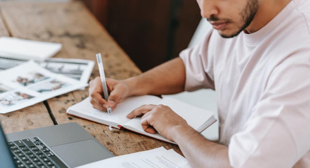 Focused individual writing in a notebook, symbolizing Harte Hanks' content marketing services. As a leading content marketing agency, we help businesses build affinity and amplify their voice with strategic content that inspires action. Perfect for brands seeking a reliable content creator agency to drive impactful campaigns.