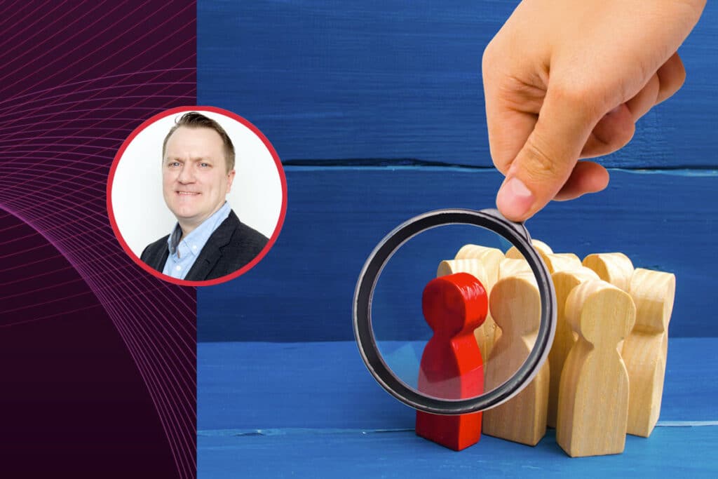 A hand holds a magnifying glass over a red wooden figure, symbolizing a CX audit to enhance customer experience strategy. The image highlights the importance of identifying gaps, refining strategies, and using voice of the customer insights to improve CX.