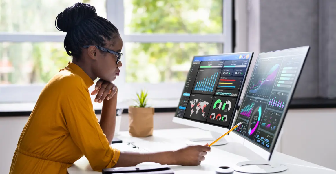 Healthcare professional using dual monitors for data analysis, symbolizing the growing importance of data analytics in healthcare. The image highlights the efforts of healthcare data analytics companies to create a data-driven culture in the healthcare industry, particularly within the pharmaceutical sector.