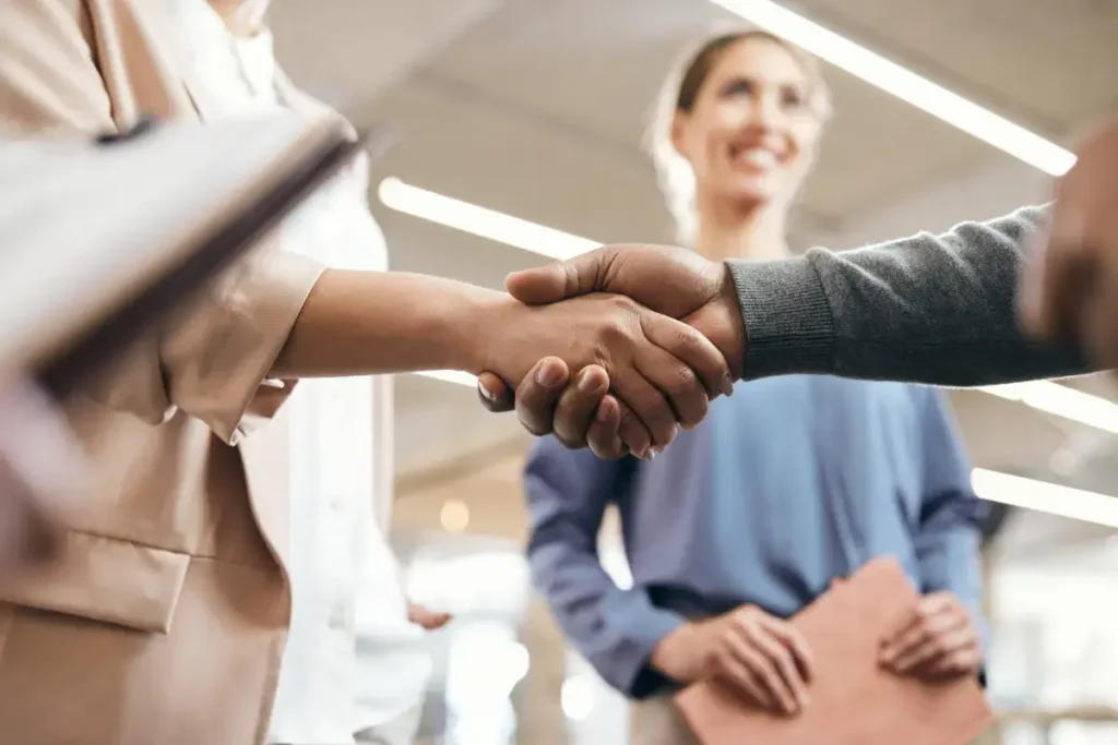 Business professionals shaking hands in a strategic partnership meeting, symbolizing collaboration and measuring ROI in partnerships using key performance metrics like partnership KPIs, success factors, and revenue growth strategies.