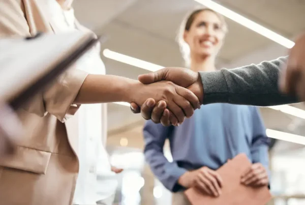 Business professionals shaking hands in a strategic partnership meeting, symbolizing collaboration and measuring ROI in partnerships using key performance metrics like partnership KPIs, success factors, and revenue growth strategies.