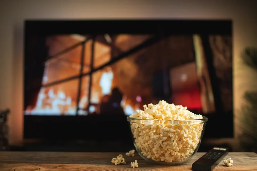 Bowl of popcorn in front of a TV screen symbolizing a global TV event and seamless customer experience, highlighting AI-driven tools, rapid scale, cost savings, and enhanced fan engagement for a hit TV series within the global media and entertainment industry.